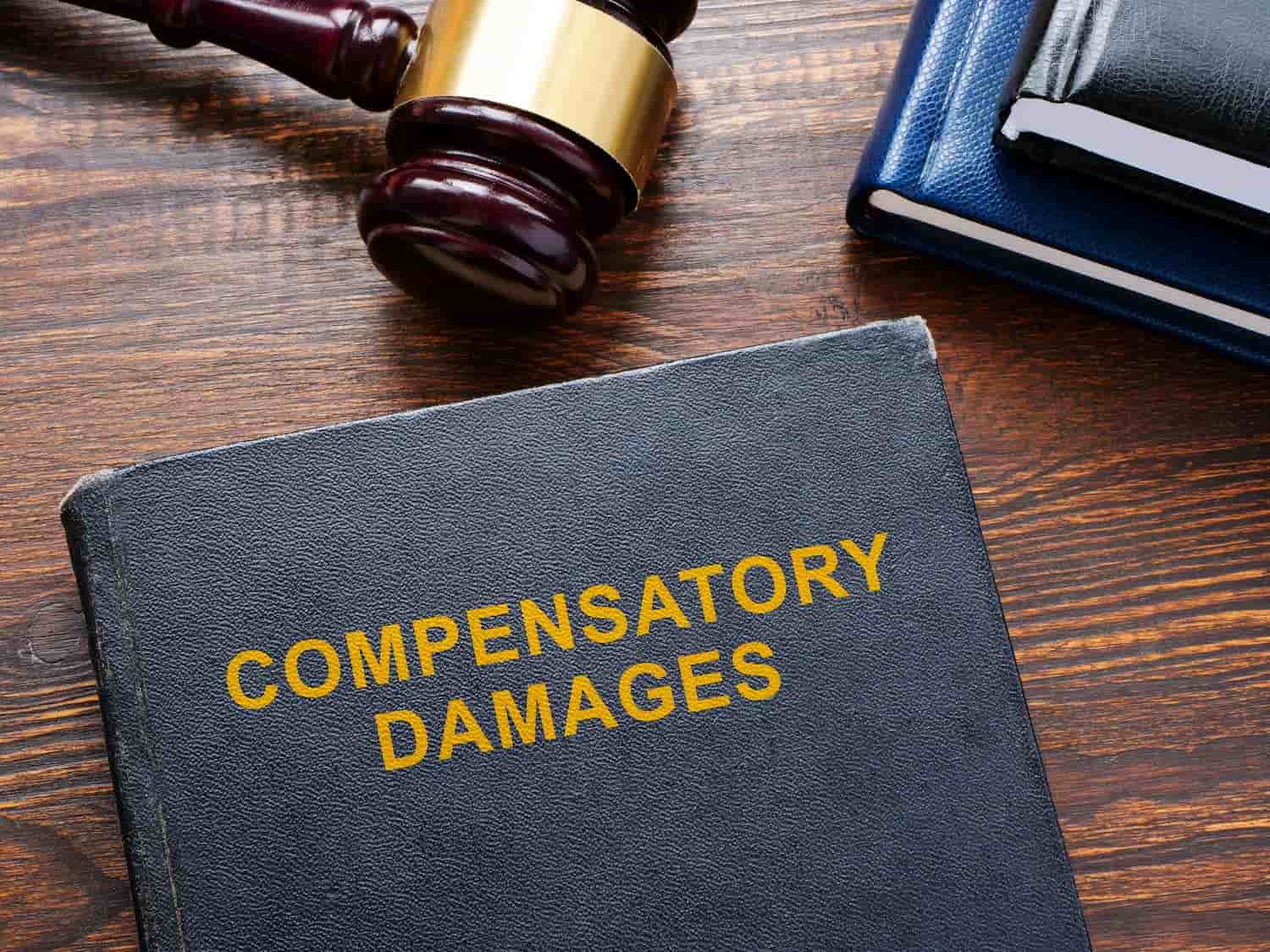 Law book labeled compensatory damages beside a judge’s gavel, representing financial compensation after a motorcycle accident in Texas