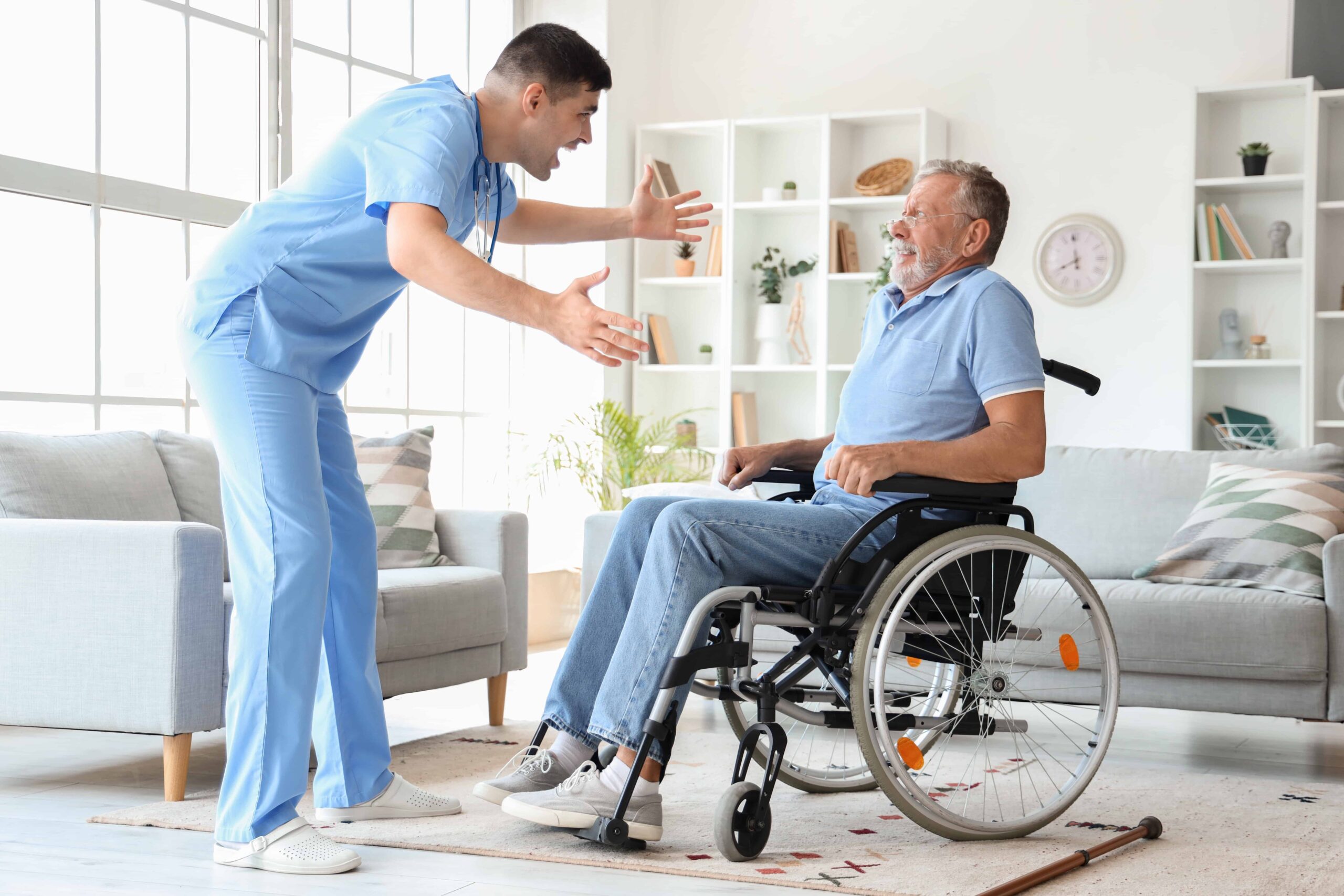 Male caregiver assisting an elderly man in a wheelchair at home, demonstrating senior care support.
