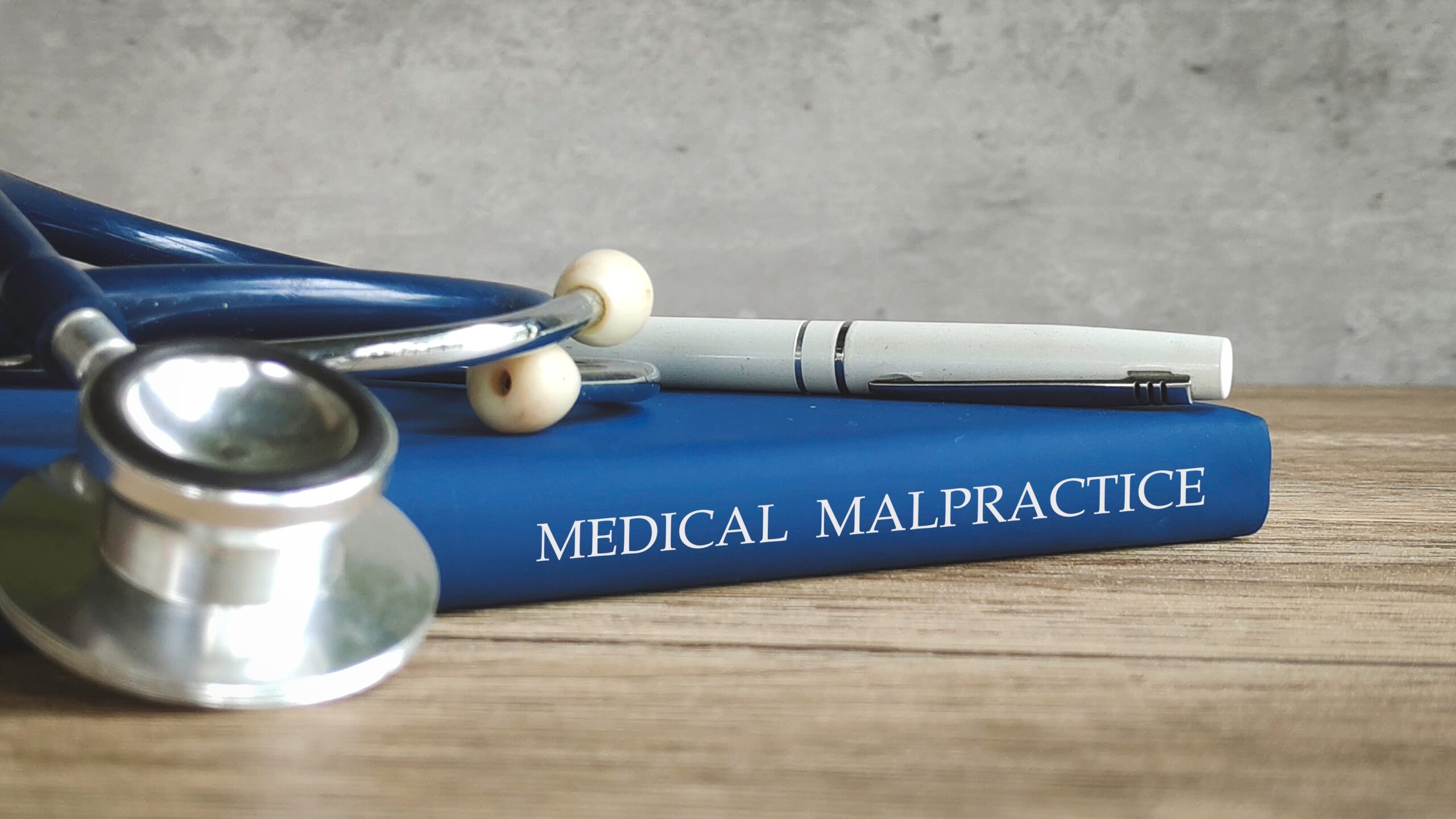 Medical malpractice law book with stethoscope and pen on a desk, representing healthcare negligence cases.